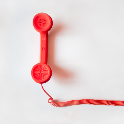 Roter Telefonhörer mit Kabel auf einem hellen Hintergrund