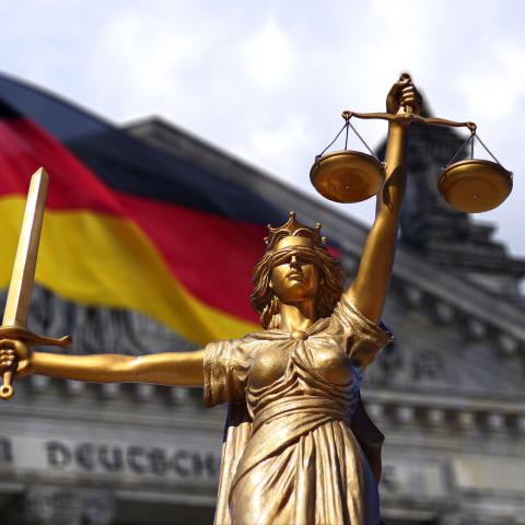 Eine Figur, die Jura symbolisiert vor der deutschen Flagge
