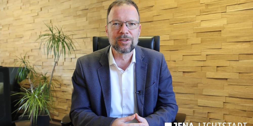 Ein Mann sitzt an einem Tisch und blickt in die Kamera.