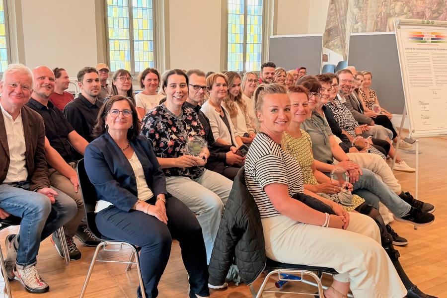 Viele Menschen in einem Raum und alle schauen in die Kamera