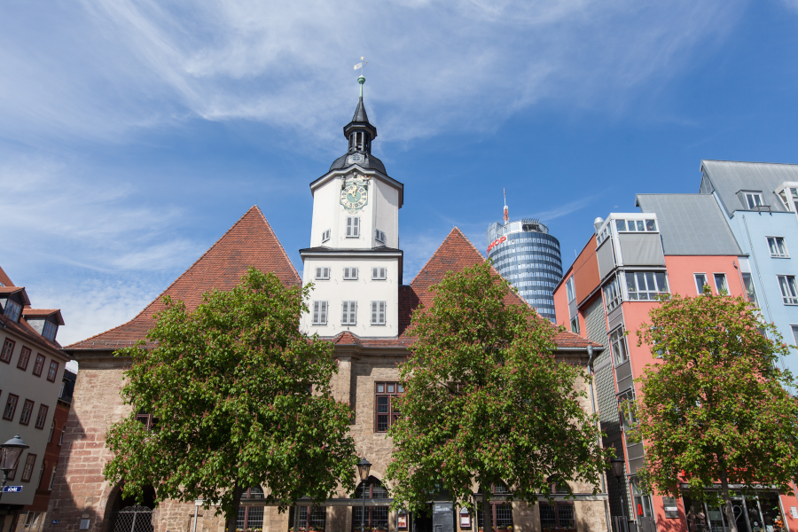 Blick auf das historische Rathaus vom Marktplatz aus, rechts daneben mehrere farbige Gebäude, im Hintergrund der Jentower