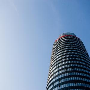 Blick von unten auf einen hohen runden Turm mit blauem Himmel im Hintergrund