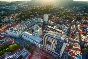 Blick auf den Jenaer Campus. Luftbildaufnahme mit Blick auf einen großen Gebäudekomplex mit Hochhäusern dahinter kleinere Häuser und Grün.