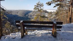 Eine Bank von hinten steht auf einem Berg mit Blick in ein verschneites Tal