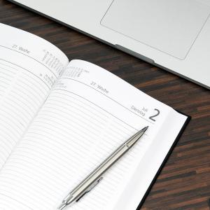 Stift liegt auf einem aufgeschlagenen Kalender, der auf einem Tisch liegt