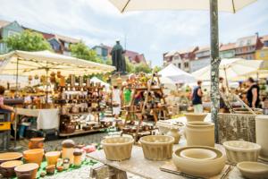 Ungebrannte Töpferwaren auf dem Töpfermarkt in Jena, mit weiteren Ständen und Publikum im Hintergrund.