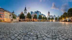 Im Vordergrund Boden mit Plastersteinen, Hintergund Häuser des Jenaer Marktplatzes mit Rathaus, Bismarckbrunnen