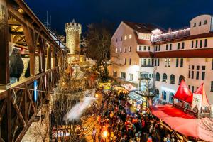 Blick von oben auf einen Platz mit einer alten Stadtmauer und einem Turm mit vielen Ständen und gemütlich beleuchtet