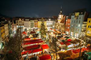 Blick von oben auf einen beleuchteten Marktplatz am Abend mit vielen Ständen