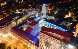 Nächtlicher Blick aus der Vogelperspektive auf einen Platz mit vielen bunt beleuchteten Gebäuden.