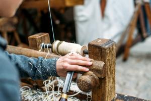 Hand eines Kindes nutzt Drechselwerkzeug an der Drechselbank