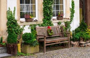 Eine Gartenbank steht vor einem Haus. Pflanzkübel stehen auf beiden Seiten der Bank.