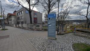 Eine Stele mit Informationen zu Robert J. Büchler und dem Todesmarsch am 11.04.1945 steht auf einem Gehweg. Im Hintergrund ist ein Schulgebäude zu sehen.