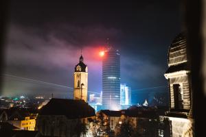 Nächtlicher Blick auf eine Stadtsilhouette mit mehreren Gebäuden, Türmen und Lichtern